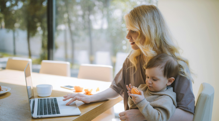 Woman-holding-baby-uses-laptop