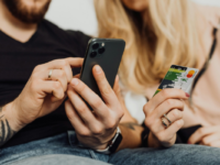 man-holding-and-tapping-iphone-sitting-next-to-woman-holding-credit-card