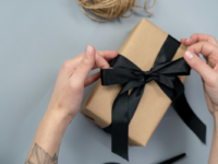 hands-tying-black-bow-on-brown-paper-packaged-gift