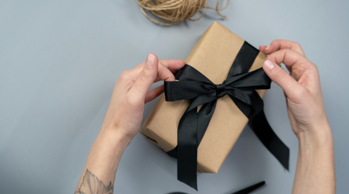 hands-tying-black-bow-on-brown-paper-packaged-gift