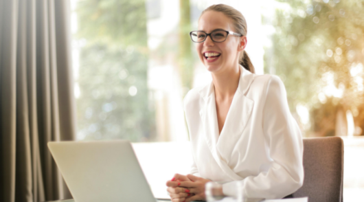 smiling-woman-with-glasses-sitting-at-desk-with-laptop