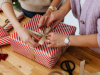 close-up-of-bow-being-tied-to-red-stripy-present