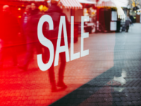 Closeup of a red sale sign inside a shop window.