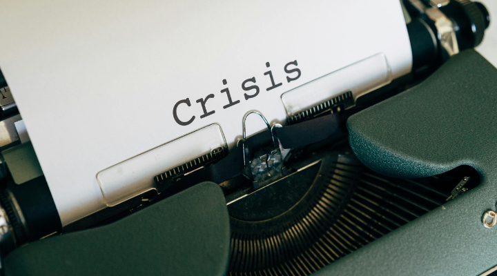 A typewriter printing the word 'crisis'.