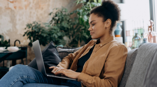 Woman in jacket using laptop on couch