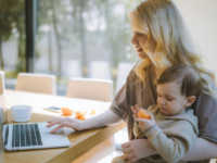 A woman working while holding a baby.