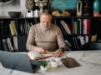 Man with grey hair looking down at laptop on desk