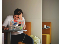 Man sitting on laptop in booth.