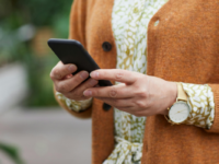 Woman in orange jumper using smartphone.